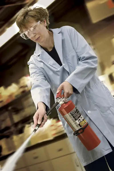 person in lab coat discharging fire extinguisher