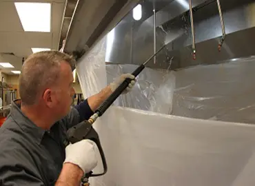 technician cleaning commercial kitchen exhaust system